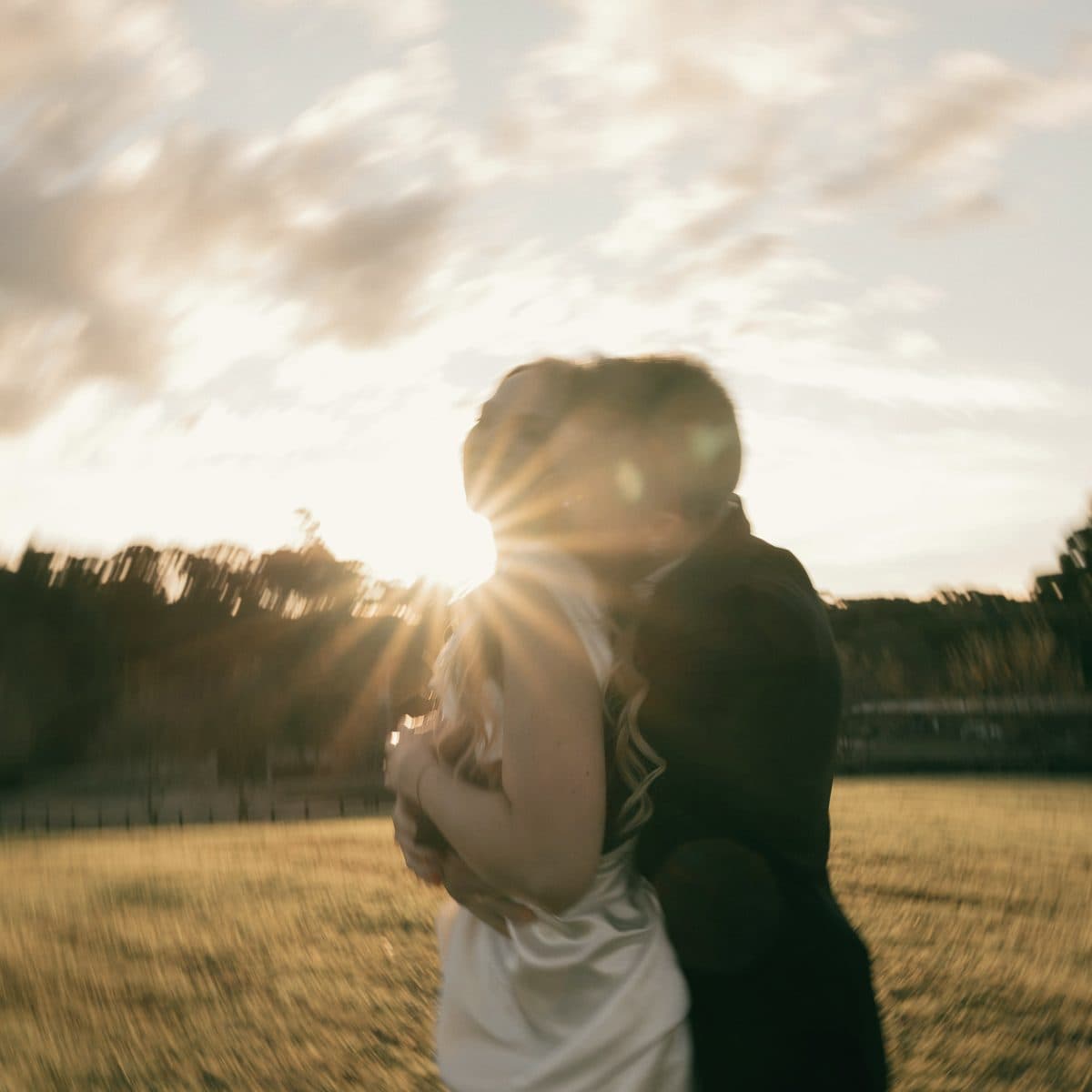 Pareja de recién casados abrazándose al atardecer en un campo